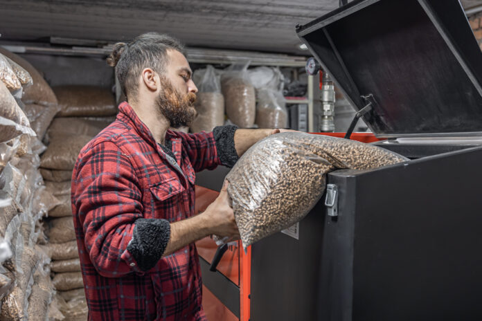 The man loads the pellets in the solid fuel boiler, working with biofuels. opał